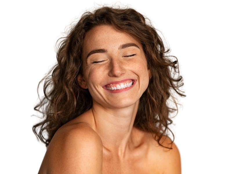 Mujer sonriendo al aire libre con la piel luminosa, imagen del concepto wellaging de Mlab